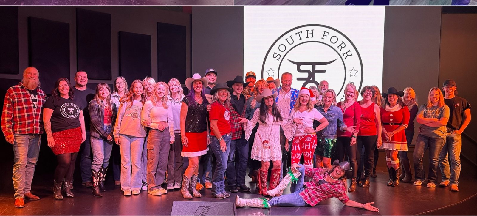 The whole group on stage under the club badge